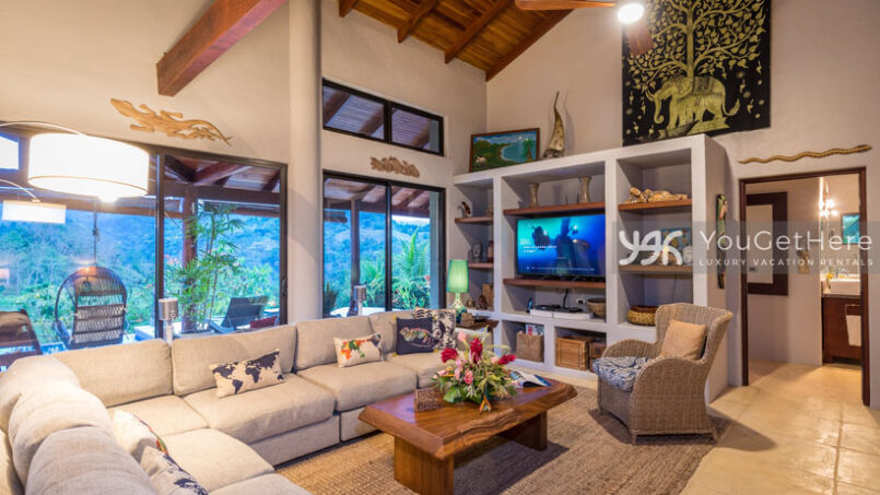 Large sectional sofa, coffee table and wicker chair in the TV area of living room at Villa Koora.
