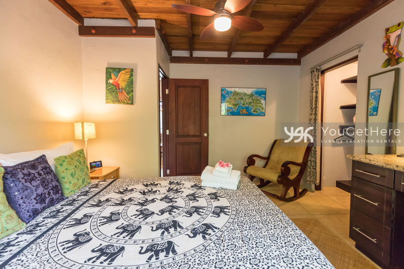 Villa Koora guest bedroom with overhead fans and comfortable rocking chair.