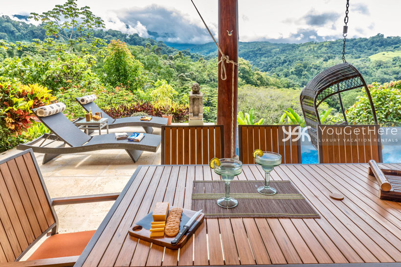Outdoor dining area with lounge chairs and hanging swing chair at Villa Koora Holiday Rental.