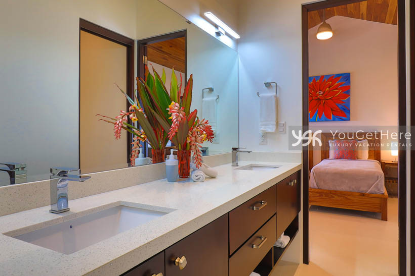 Villa Dalu modern guest bath with dark wood cabinetry and sleek white countertops.