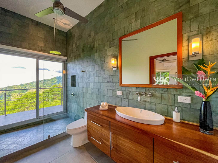 Tulu Azul Costa Rica beautifully tiled bathroom with wooden cabinets and overhead rainfall shower with view of jungle.