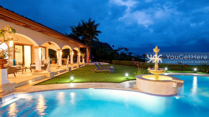 Vista Encanto Costa Rica lighted pool and patio at nighttime with ocean view background.