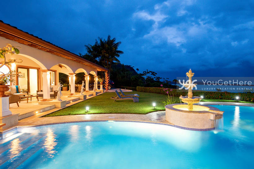 Vista Encanto Costa Rica lighted pool and patio at nighttime with ocean view background.