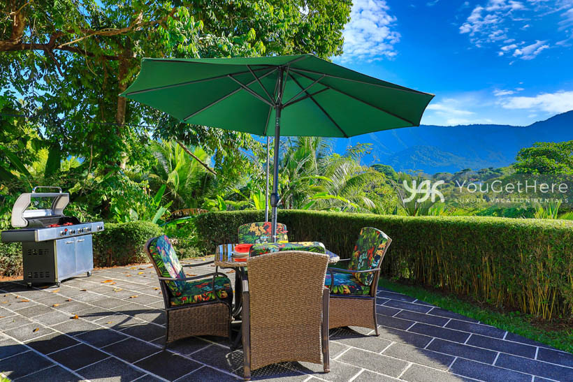 Vista Encanto Costa Rica Outdoor grilling area with BBQ and table for four with shade umbrella.
