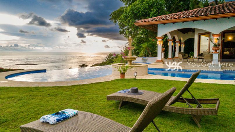 Ocean view over the pool at Vista Encanto Costa Rica with two loungers in the fresh cut grass.