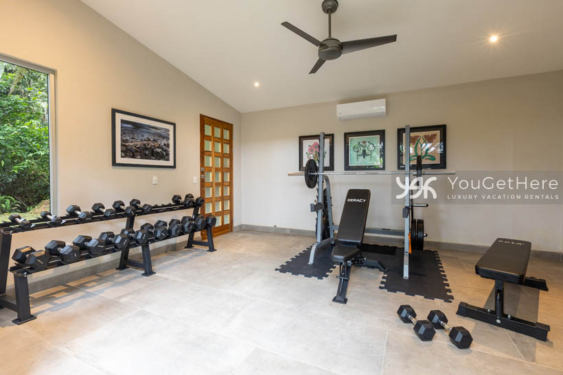 The exercise room with free weights, benches, yoga space, AC and ceiling fan at Tulu Azul Costa Rica.