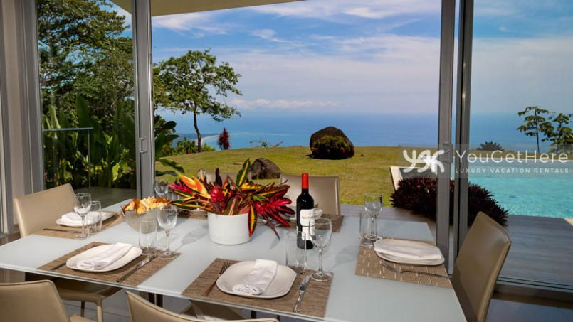 View of ocean and green outdoor spaces from inside at the dining table for six.