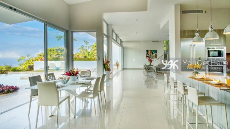 Huge spacious and bright off-white tiled dining area with full walled glass sliders that open onto pool deck.