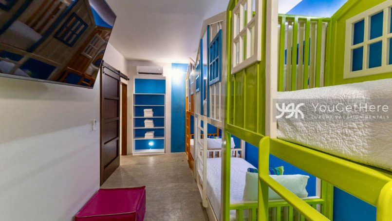 Three bright colorful bunk beds, a TV and closet in the kids room at the Jade House Costa Rica.