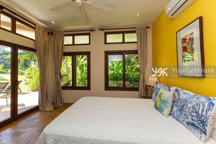 Caballitos del Mar Norte vacation villa bedrooms with pool view and green landscaping outside.
