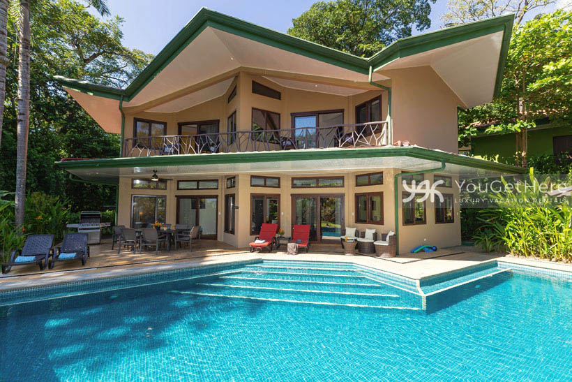 Two story vacation rental with second floor balcony, large pool and spacious pool deck with ample seating.