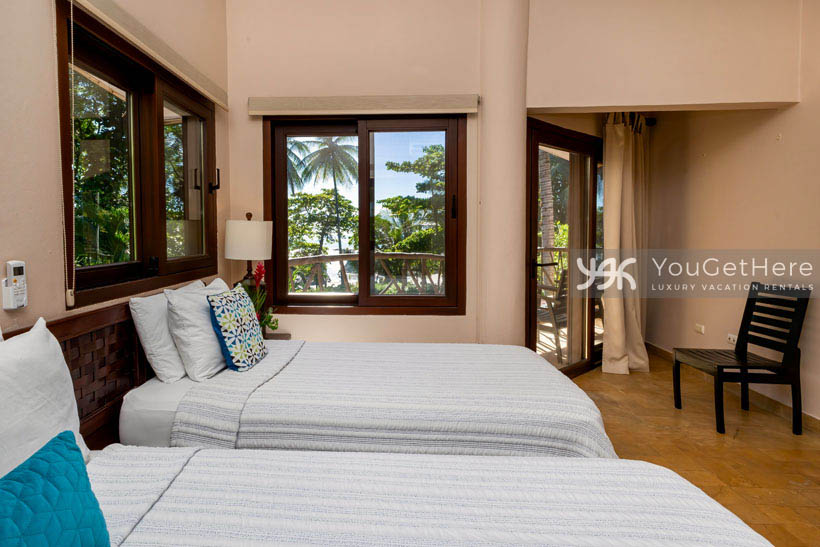 Caballitos del Mar guest bedroom with two beds and a slider onto the balcony.