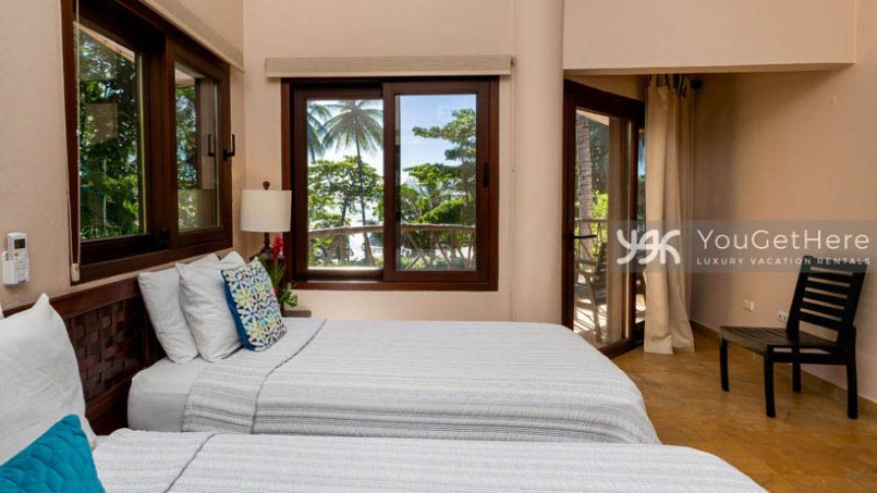 Caballitos del Mar Central guest bedroom with two beds and a slider onto the balcony.