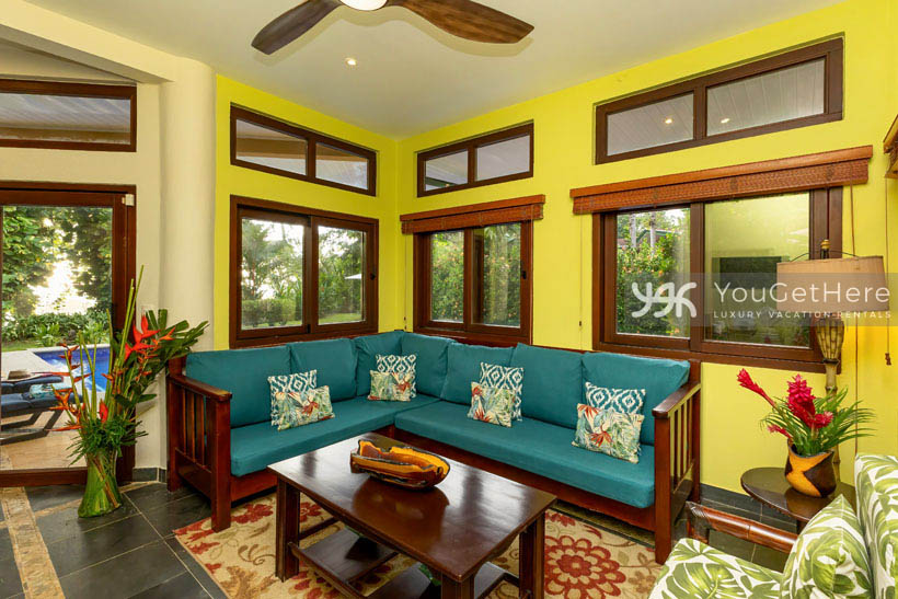 Bright and colorful living room with tropical flowers and comfortable sofa and chair.