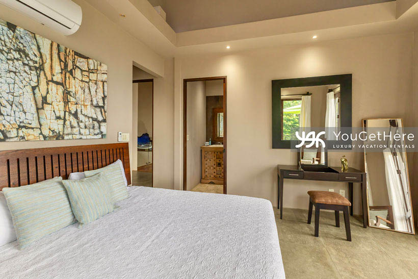 Jade House Costa Rica guest bedroom with king seized bed, air conditioning, and vanity table and seat.