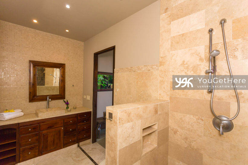 Jade house Costa Rica guest bathroom with natural stone detail, ample counter space and lovely wood cabinetry.