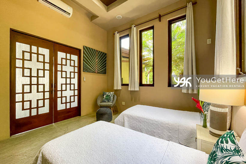 Jade house Costa Rica lovely comfortable guest bedroom with two twin beds, AC, soft lighting and beautiful wood work and vaulted ceilings.