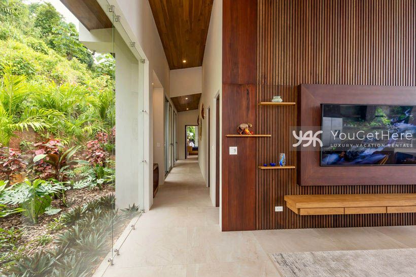 Huge glass walls in luxury vacation villa for guests to enjoy tropical garden landscaping from the comfort of the oversized sofa.