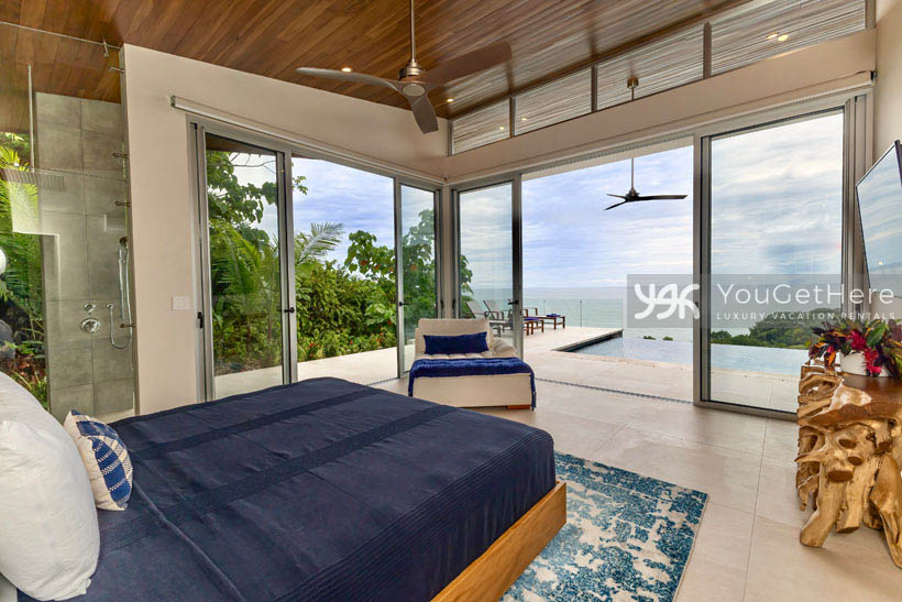 Master suite in Costa Rica vacation villa with full ocean views through sliding glass door out to infinity pool and deck.