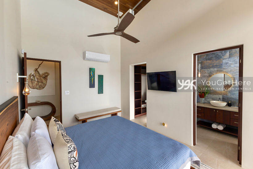 Comfortable guest suite featuring en-suite bathroom, air conditioning, overhead fan and wall-mounted television under vaulted ceilings.