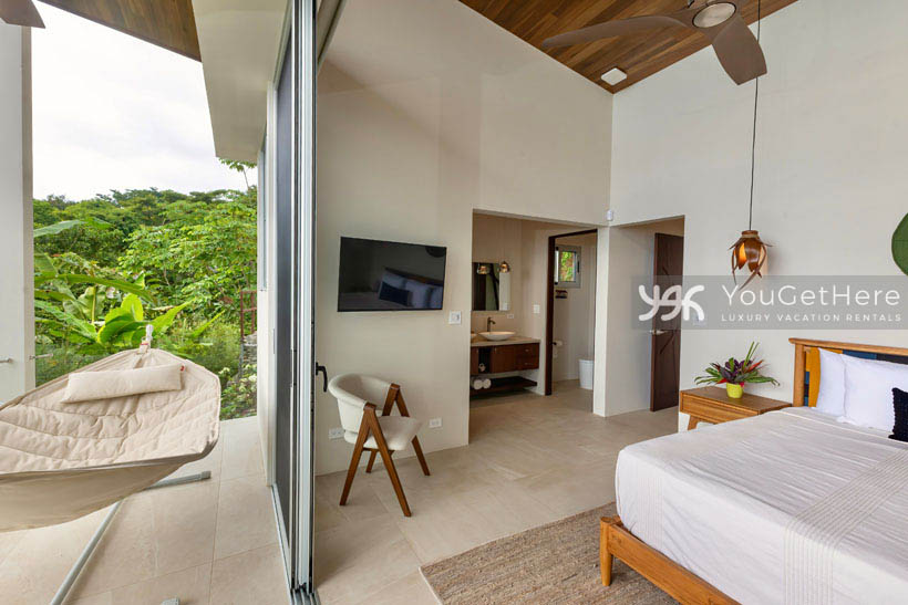 Oversized glass slider off of guest suite opening to a comfortable padded hammock for relaxing ocean view.