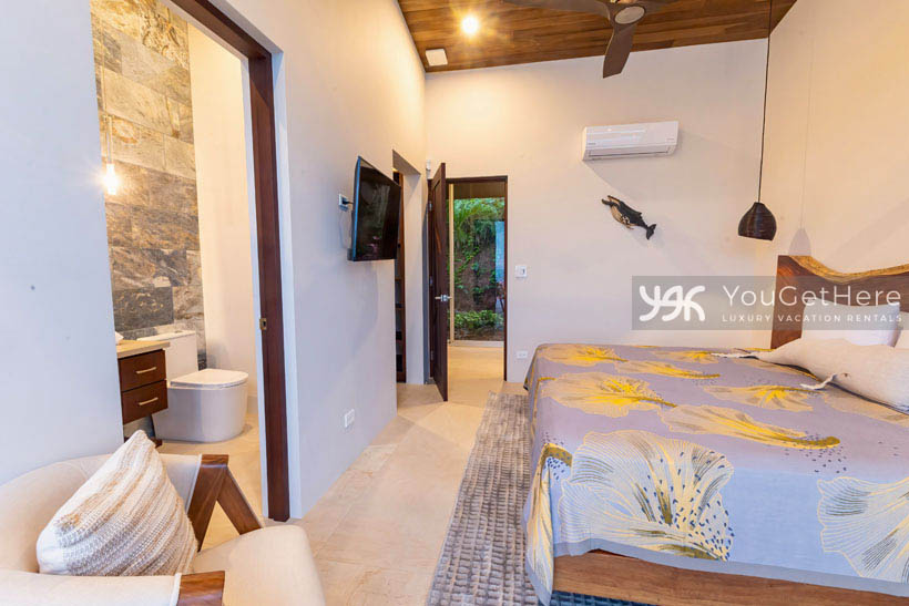 Comfortable air conditioned guest bedroom with en-suite bathroom and wall-mounted flat screen television.