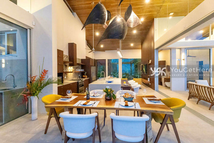 Beautifully crafted wood dining table seating six under stunning lighting decor in luxury villa Costa Rica.