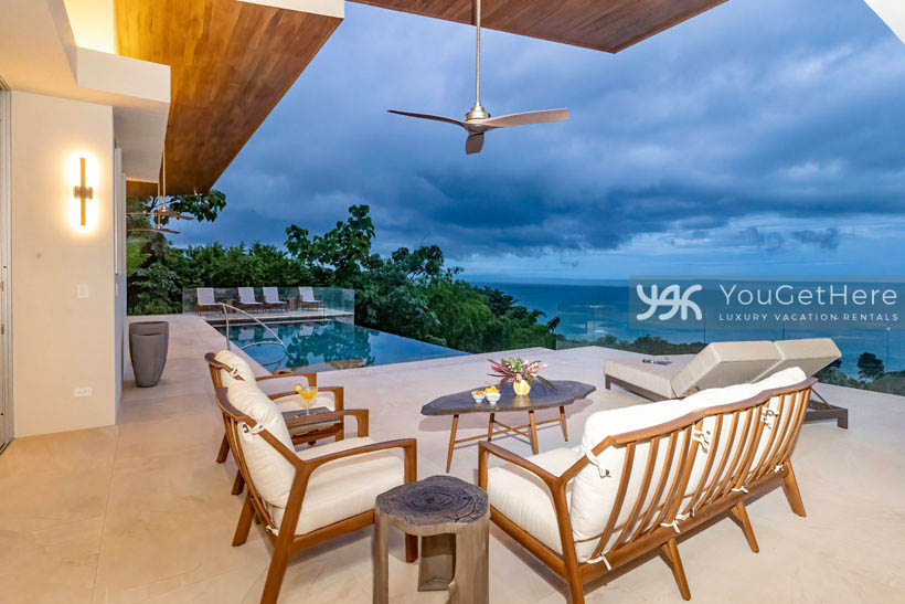 Outdoor seating area at Costa Rica vacation home with panoramic ocean views, immaculate pool deck and infinity pool.