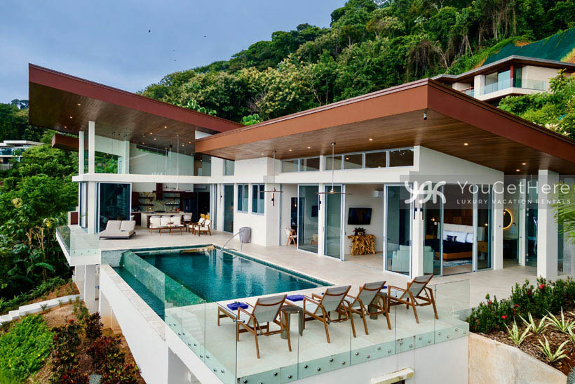 Costa Rica luxury vacation rental with poolside lounge chairs and two person lounger overlooking the ocean.