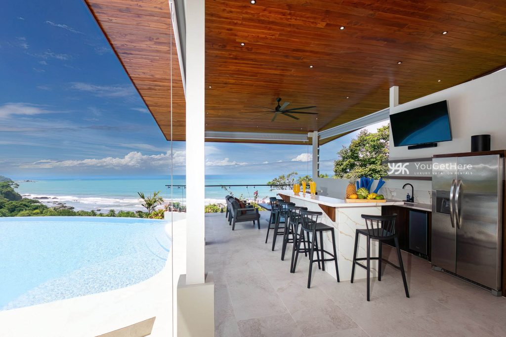 Villa Aura Dominical Outdoor pool side bar and kitchen with lounge chairs and TV.